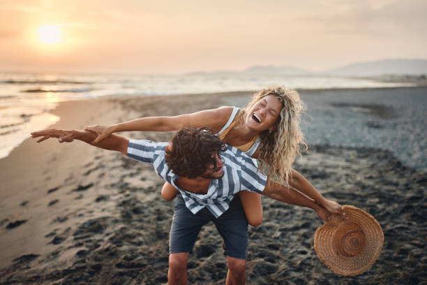 istock Cheerful couple having fun while piggybacking on the beach at sunset. 2154238253