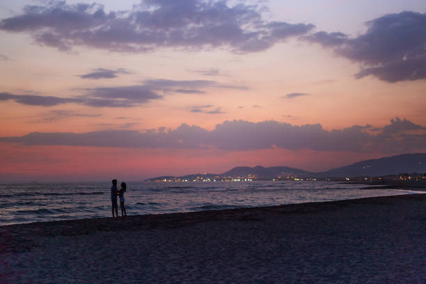 Romantic couple in love talking during summer sunset on the beach. Copy space.