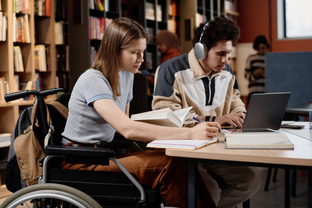 istock Student With Disability And Her Friend At Library 2154239976