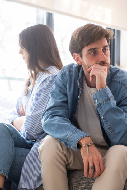 istock Engaged couple with relationship problems sitting on the sofa with their backs to each other after an argument, conflicts in marriage, upset couple after a dispute, making decision to break up and divorce 2154244249