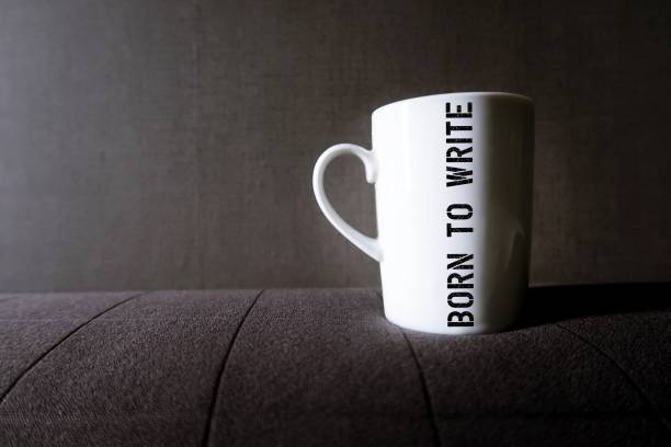 istock White coffee cup mug on gray copy space background with screen on the side BORN TO WRITE , refers to an inspiring passionate writer , one who have passion to write 2154244307