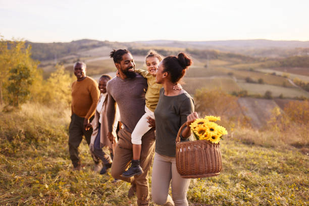 Happy African American extended family going on a picnic in autumn day. Happy black multi-generation family enjoying while going on a picnic in autumn day on a hill. black african girls pictures stock pictures, royalty-free photos & images