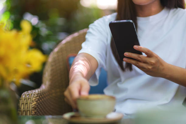 istock Closeup image of a woman using mobile phone and drinking coffee in the outdoors cafe 2154244523