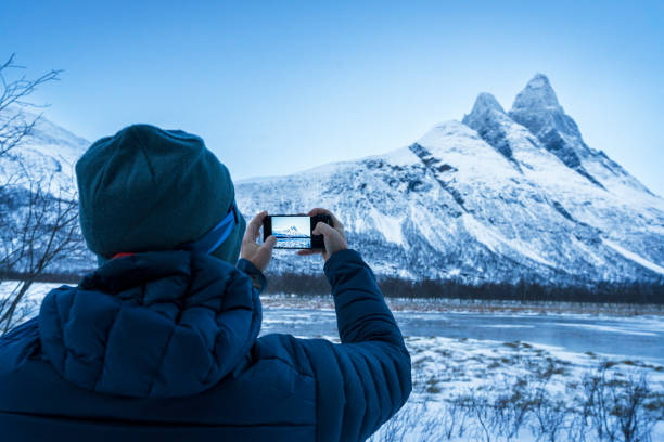 istock Hiker photographing snowy peak in winter, Norway 2154246405