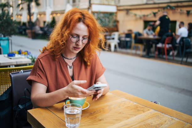 istock Happy young redhead woman  in cafe  drinking coffee and using smart phone 2154248177