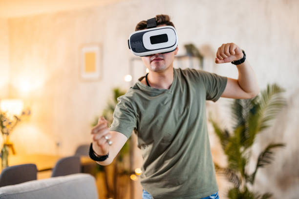 istock Young Man Playing A Game On A Virtual Reality Headset At Home 2154249973