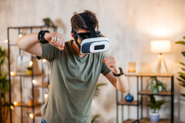 istock Young Man Playing A Game On A Virtual Reality Headset At Home 2154250269