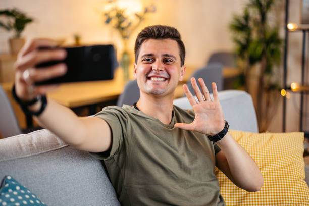 istock Young Man Having Video Call On The Sofa At Home 2154250648
