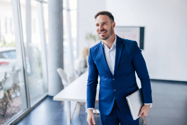 Confident business person with laptop walking