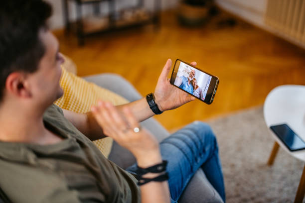 istock Young Man Having Video Call With His Parents On The Sofa At Home 2154251488