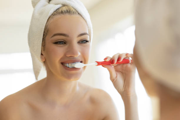 istock Woman brushing teeth with toothbrush and looking in mirror 2154251667