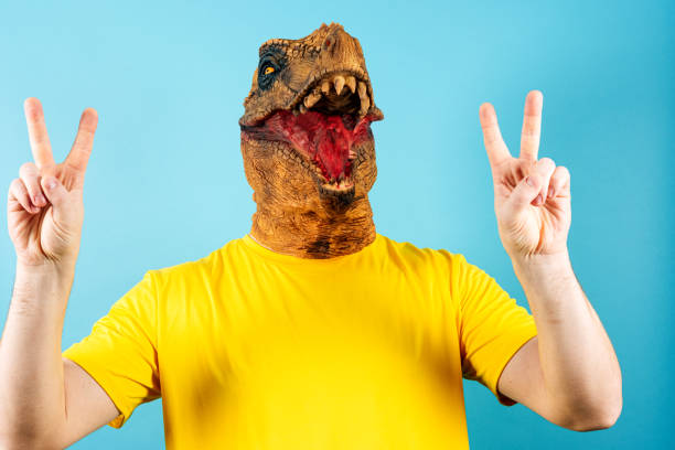 istock Person in dinosaur mask showing peace signs with both hands 2154252546