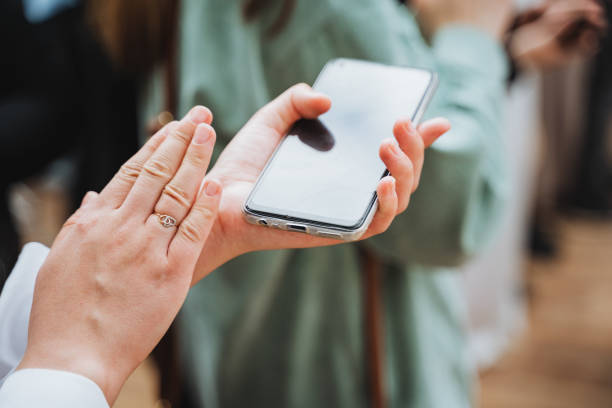 istock Hand holding a cell phone, thumb swiping screen, sharing information 2154252860