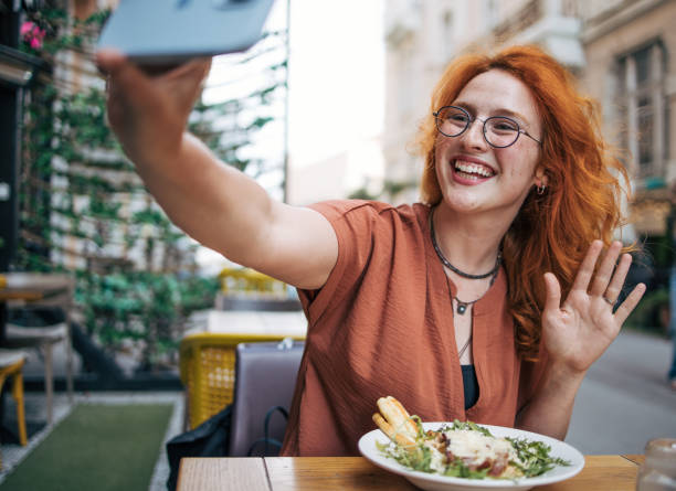istock Happy young redhead woman eating Caesar salad in restaurant 2154253374