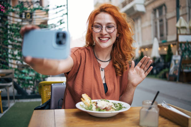 istock Happy young redhead woman eating Caesar salad in restaurant 2154253396