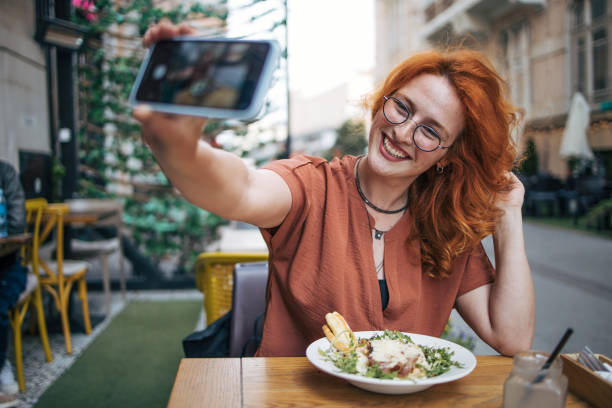 istock Happy young redhead woman eating Caesar salad in restaurant 2154253567