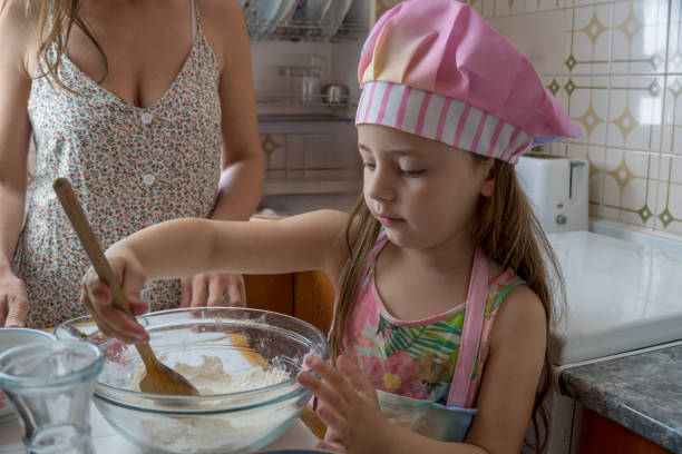 istock Girl and Mom Cooking Sweets in Home Kitchen 2154258804