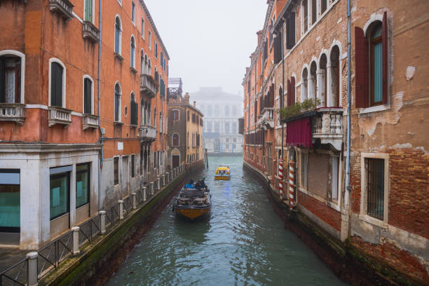 Canal between residential buildings in Venice with boats navigating, travel destinations in Italy