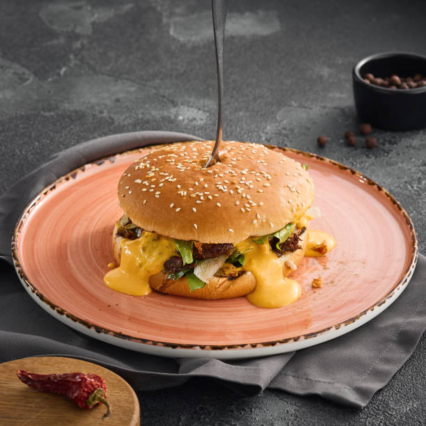 A succulent pulled beef burger dripping with rich cheese sauce, served on a plate for a mouthwatering meal