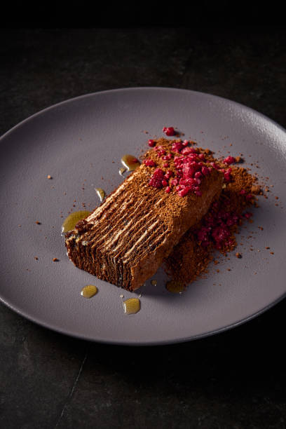 istock Close-up from a vertical side angle, showcasing the delightful Medovik honey cake with raspberries, set against a minimalist black tableau 2154265929