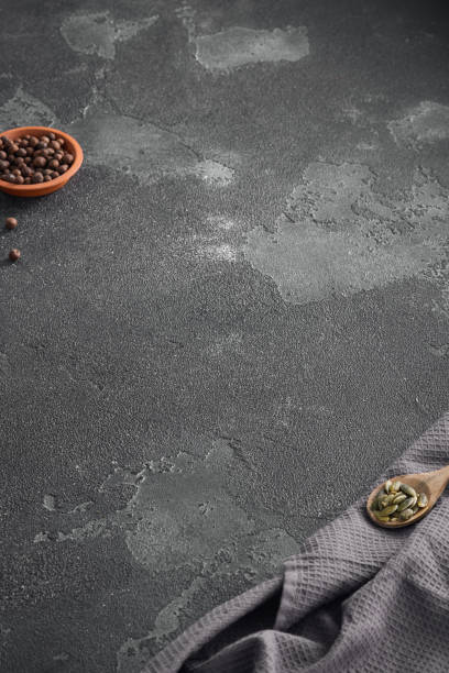 istock Textured dark grey background ideal for food presentation, featuring a terracotta bowl of peppercorns and a wooden spoon of pumpkin seeds 2154265942