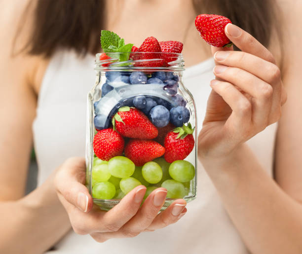 istock hands with a jar of various summer berries 2154270442