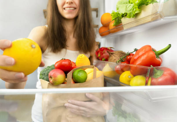 istock woman putting shopping from bag into refrigerator 2154270606