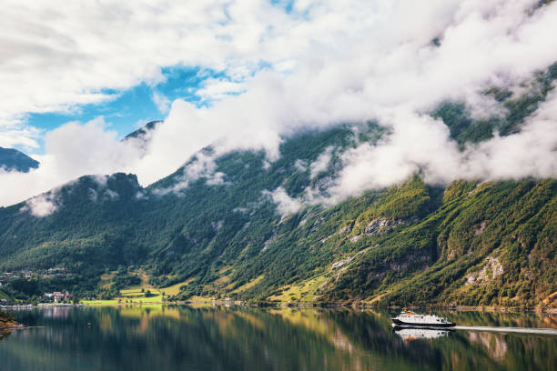 Ferry crossing scenic Geirangerfjord fjord in Norway surrounded by misty mountains