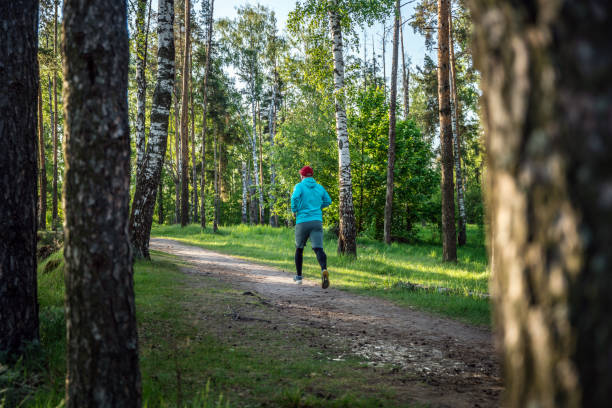 A young male runner running on asphalt road in fall season. Side shot, Off focus, blurred image.