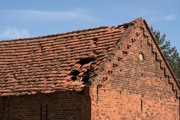 Unrenovated, partially damaged red tile roof on an old brick building