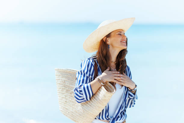 istock happy elegant woman on ocean shore with straw bag 2154284015