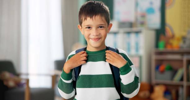 istock Child, face and laughing in school classroom or education with backpack for kindergarten, learning or joke. Boy, kid and portrait for study development on academy campus or student, humor or funny 2154290474