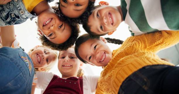 istock Huddle, support and happy children in school for education, community or development. Low angle, diversity and group of friends with smile in playground for solidarity, teamwork or playing together 2154290512