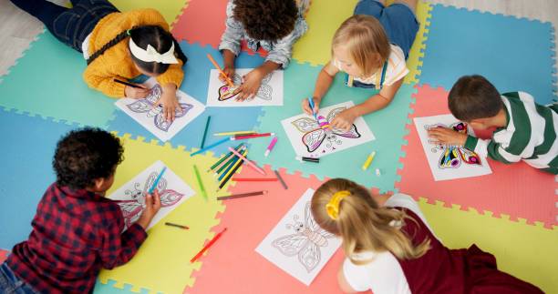 istock Children, group and drawing for creative learning in classroom for education, project or back to school. Boys, girls and friends on floor mat for student art lesson or Montessori, youth or playing 2154290516