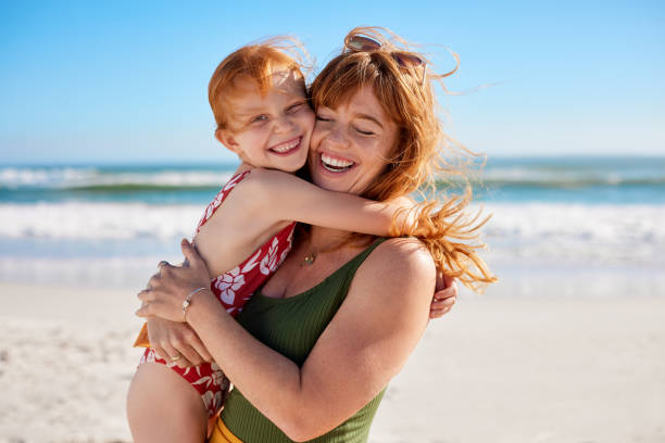istock Mother and daughter with red hair having fun at beach while hugging 2154294330