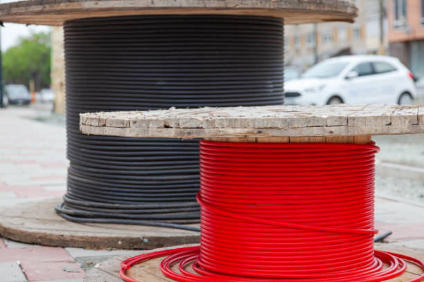 Two wooden spools with new electrical cables wrapped in black and red.