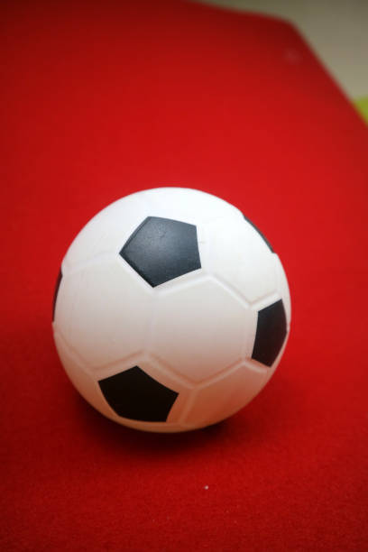 istock a small white and black toy rubber ball. Red background 2154301804