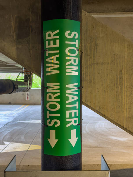 istock Closeup view of a metal pipe labeled storm water within a concrete parking garage, structure. 2154304694
