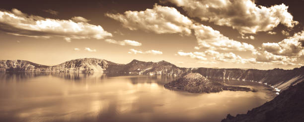 Panorama landscape photography of Crater Lake in Ontario with a mirror-like surface and Wizard Island, cloudy sky, sepia toned, monochrome