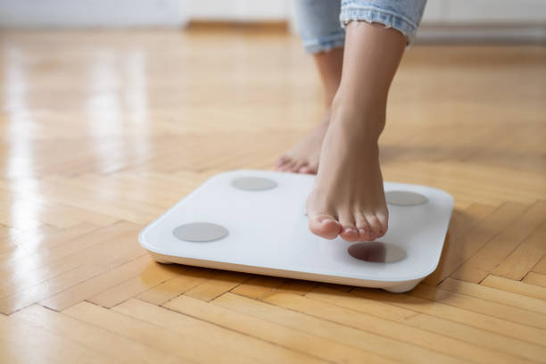 istock Young woman standing on scale 2154309427