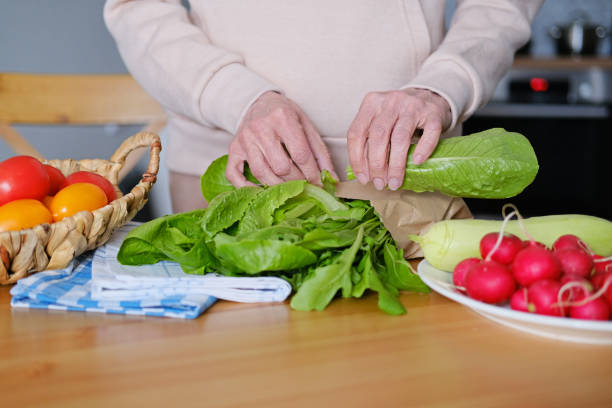 istock Aged woman cuts fresh vegetables and herbs for salad 2154311590