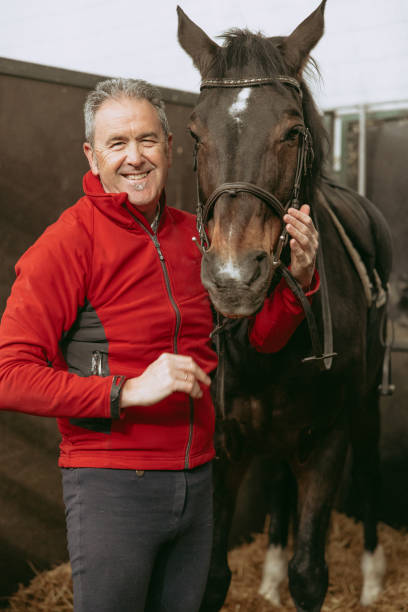 istock Happy man smiling and embracing horse in stable. 2154313939