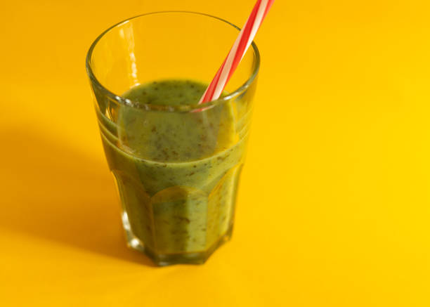 green smoothie drink in a glass with a straw, background