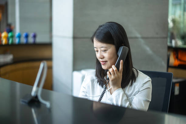 istock young woman using telephone in office 2154318410
