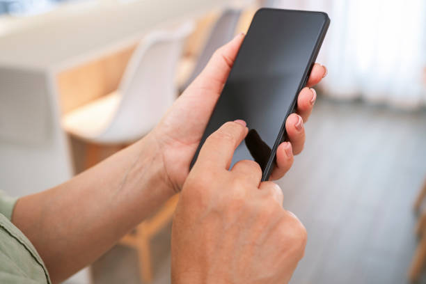 istock Woman hands holding smartphone with blank screen over blurred home interior background 2154324956