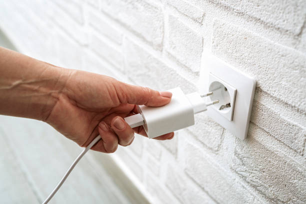 istock Close up of hand inserting device charger plug in electrical wall socket 2154324996