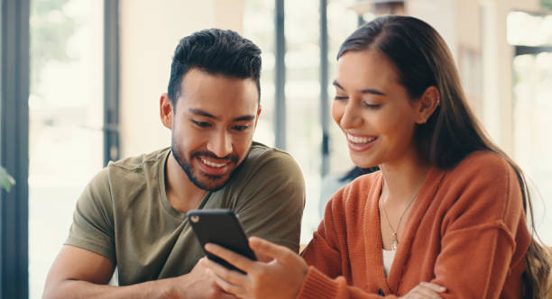 istock Couple, phone and laugh on date in cafe, reading or relax with comic video, idea or memory on mobile app. Woman, man and smartphone on social media for bonding, story or meme with love in coffee shop 2154330574