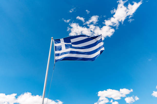 Greek flag waving in the wind against blue sky.