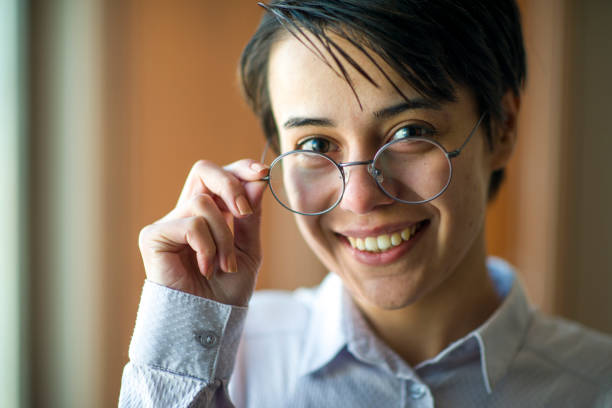 Businesswoman with short hair in a white shirt and black trousers working in an office environment and making a phone call