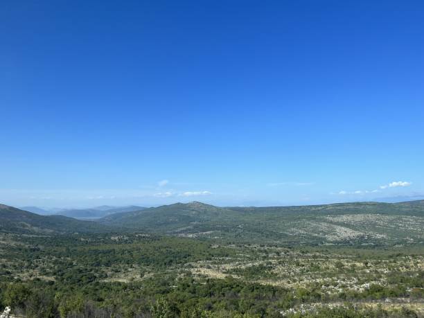 istock Panoramic View of Rolling Hills and Clear Blue Sky in Bosnia 2154338113